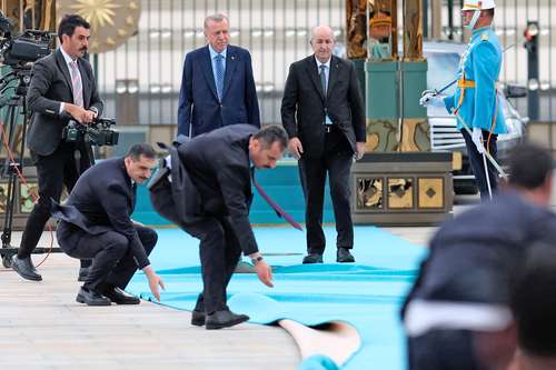 Personal de seguridad arregla la alfombra al paso del presidente turco, Recep Tayyip Erdogan (a la izquierda), quien recibió a su homólogo de Argelia, Abdelmayid Tebune.