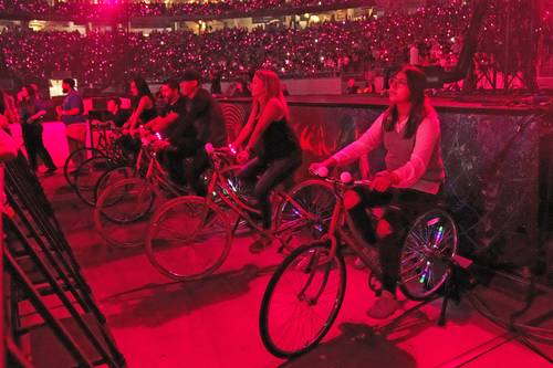 Asistentes a la gira de Coldplay Música de las esferas en Arizona pedalean bicicletas que producen electricidad para la realización del concierto.