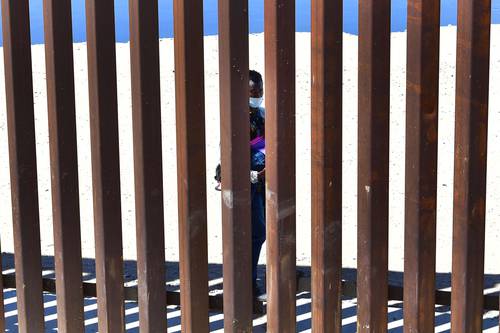 Un migrante camina del lado mexicano del muro fronterizo frente a Yuma, Arizona.