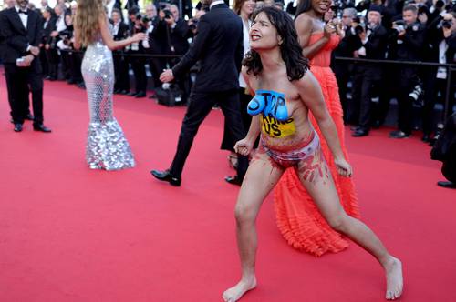  Una mujer con los colores nacionales ucranios pintados en su cuerpo y la leyenda “Dejen de violarnos” protesta en la alfombra roja del 75 Festival Internacional de Cine de Cannes, mientras los invitados llegaban para la proyección la película Tres mil años de añoranza. Foto Afp