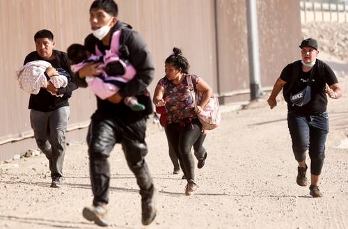 Luego de que un juez federal impidió la conclusión del Título 42, un grupo de migrantes corre para atravesar por un hueco la barrera fronteriza hacia Yuma, Arizona.