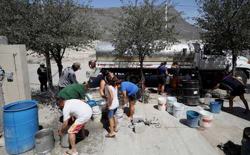 Trabajadores de la Conagua abastecen el líquido en tinacos, ollas, cubetas y garrafones a pobladores de la colonia Hacienda del Renacimiento, municipio de García, Nuevo León.