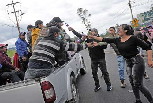 Pobladores de la ciudad de Tambillo regalan botellas de agua a indígenas que marchan en caravana hacia Quito, en repudio a medidas económicas del gobierno.
