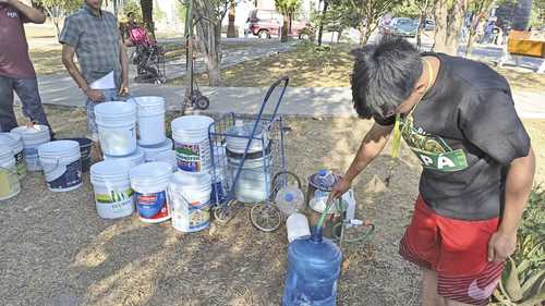 Habitantes de la colonia Industrias, en San Nicolás de los Garza, se abastecen de agua en una toma de un parque.