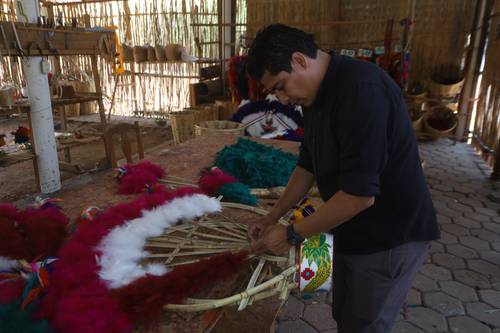 Ivan Cruz López elabora los penachos que los danzantes lucirán durante la festividad.