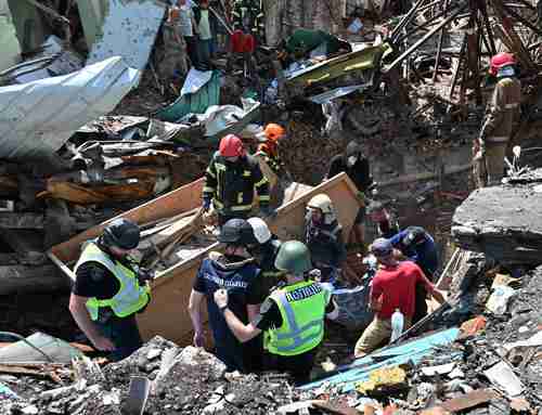 Rescatistas extraen el cuerpo de una mujer de entre los escombros de la Casa de Cultura, destruida ayer por un cohete ruso en Chuguev, en el este de Ucrania.