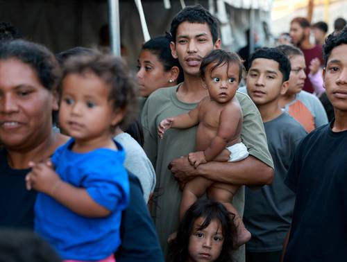 Tras cruzar la frontera, venezolanos hacen fila en un refugio migratorio en El Paso, Texas, en espera de comida.