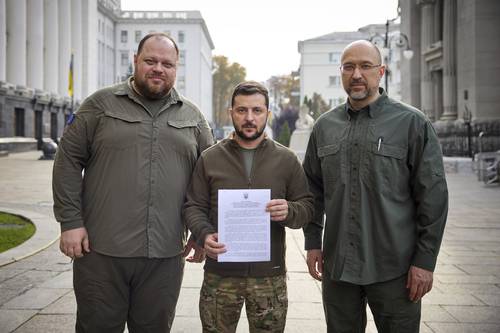 El presidente de Ucrania, Volodymir Zelensky (centro), muestra junto con el primer ministro Denis Shmyhal (derecha) y el titular de la Suprema Corte, Verkhovna Rada, la solicitud para acelerar la adhesión de su país a la OTAN.