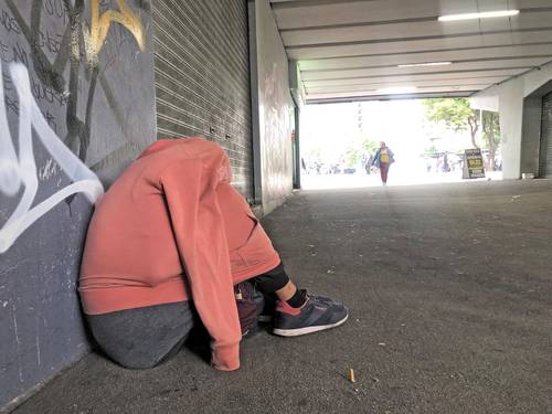 Una persona que al parecer pernoctó en la parte inferior de la glorieta Insurgentes se cubre con lo que puede del frío matinal.