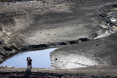 Una pareja contempla lo que fue un antiguo puente de carga expuesto por los bajos niveles de agua en el embalse de Baitings, en Yorkshire, cuando se reportaron temperaturas récord en Ripponden, Inglaterra, en agosto pasado. La sequía afectó gran parte de Europa, Estados Unidos y China el verano pasado.