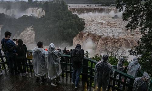 Turistas contemplan las cataratas de Iguazú desde el lado brasileño en la frontera con Argentina, cerca de Foz do Iguaçu, estado de Paraná. La cantidad de agua ha aumentado de manera significativa en los últimos días debido a las fuertes lluvias en la región. Mientras el caudal medio suele ser de 1.5 millones de litros de agua por segundo, el actual es de 13.7 millones.