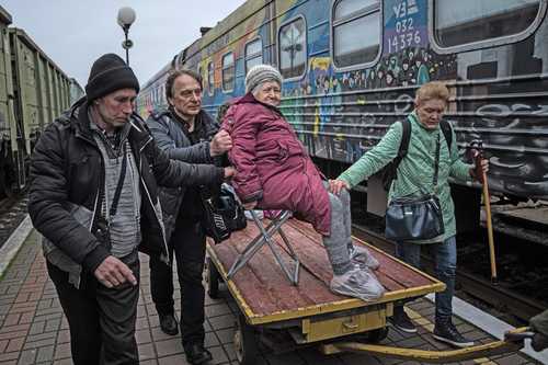 Familiares de Elizaveta, de 94 años, la transportan en un carrito de carga al tren destinado para evacuar la ciudad de Jersón.