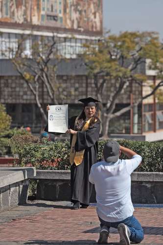 Una recién egresada de la licenciatura en administración posa para una sesión de fotos a un costado de la torre de Rectoría.