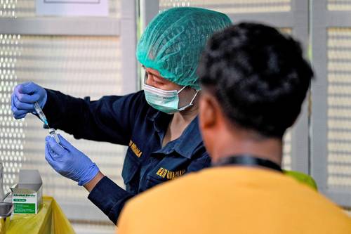 Personal de salud prepara dosis de refuerzo contra el SARS-CoV-2 para empleados en el aeropuerto de Bali.