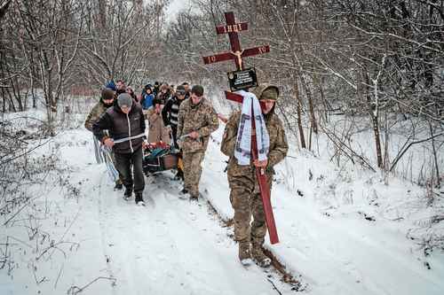 Oleksiy Storozh, de 28 años, carga una cruz para colocarla en la tumba de Oleksandr Korovniy, su difunto mejor amigo, un militar ucranio del batallón Azov, muerto en acción en Bakhmut, mientras otras personas, detrás de él llevan el ataúd de Korovniy a un cementerio en la ciudad ucrania de Sloviansk.