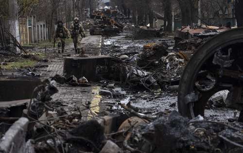 Soldados ucranios caminan en medio de tanques rusos destruidos en Bucha, a orillas de Kiev, en abril de 2022.