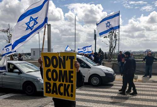 “No vuelvas”, se lee en el cartel de un manifestante en las inmediaciones del aeropuerto de Tel Aviv, en alusión al premier Benjamin Netanyahu, quien viajó ayer a Alemania.