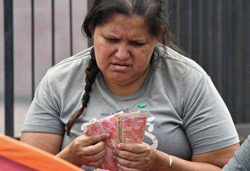  Frente al Banco Central de Honduras, en Tegucigalpa, una venezolana cuenta billetes de este país recolectados en la calle, para continuar su viaje hacia Estados Unidos. Foto Afp