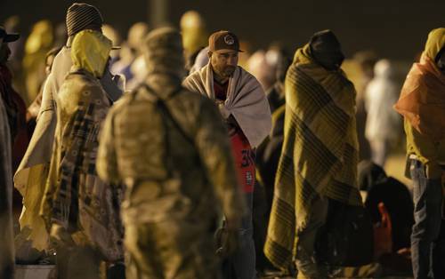 Luego de cruzar de Juárez a El Paso, migrantes esperan en el frío de la noche a ser procesados por agentes de EU.