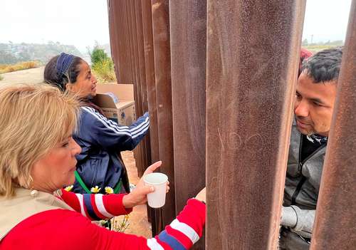 Este fin de semana, organizaciones humanitarias dieron de comer a los migrantes a través de los barrotes de la valla.