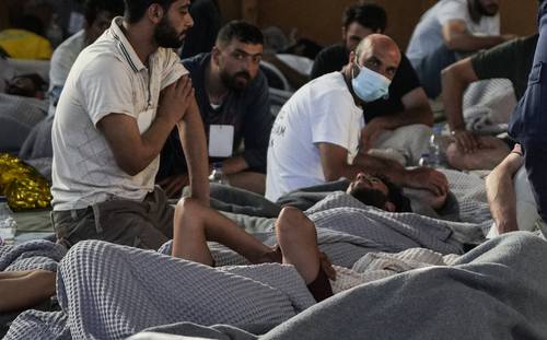 Migrantes sobrevivientes del naufragio en el sur de Grecia descansan en un almacén del puerto de Kalamata, habilitado para servir de refugio.