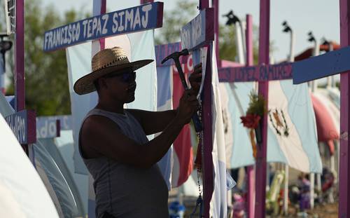 Christian Rodríguez pega un poema en una cruz que forma parte de un monumento improvisado en el sitio donde hace un año fue encontrado un semirremolque con decenas de migrantes muertos en San Antonio, Texas.