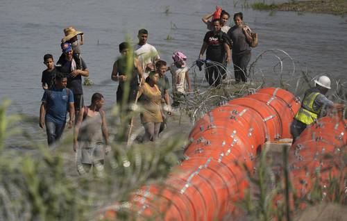 Migrantes junto al cerco fronterizo flotante puesto para evitar su paso entre Eagle Pass y Piedras Negras.