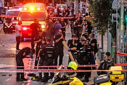 Miembros de las fuerzas de seguridad israelíes reúnen y registran pruebas dentro de la parte acordonada de una calle en Tel Aviv, donde tuvo lugar el ataque del palestino.