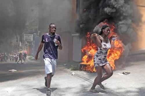 Manifestantes escapan del gas lacrimógeno que lanzó la policía ayer, cuando se dirigían a la residencia oficial del primer ministro haitiano, Ariel Henry, para exigir un freno a la violencia de las pandillas.