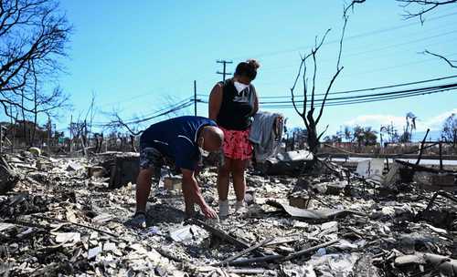 Una pareja regresa a las ruinas de su hogar en Lahaina, al este de Maui, luego de los siniestros en este condado.