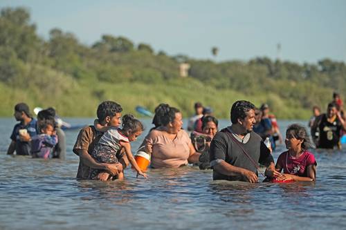 Personas rodean un alambre de púas en el río Bravo después de cruzar la frontera de México con Estados Unidos, en Eagle Pass, Texas.
