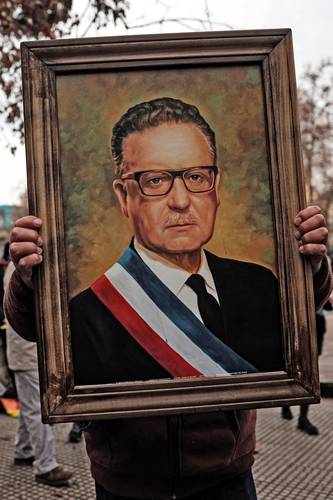 Un joven muestra un retrato del presidente Salvador Allende fallecido en 1973 a consecuencia de la asonada militar.