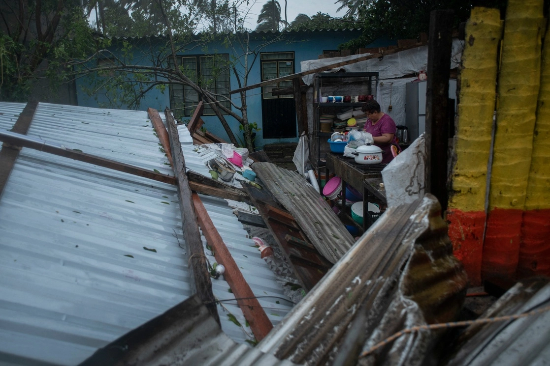 Una mujer realiza labores en su hogar, cuyo techo de lámina se vio afectado por los fuertes vientos, en Tecolutla, Veracruz. Foto Afp