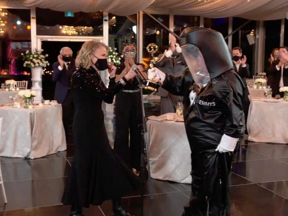  La canadiense Catherine O'Hara recibe de un mensajero con traje anti-Covid el Emmy a mejor actriz de comedia pWor Schitt's Creek, durante la 72a ceremonia de los premios Primetime Emmy. Imagen tomada de captura de pantalla cortesía de ABC, vía Afp