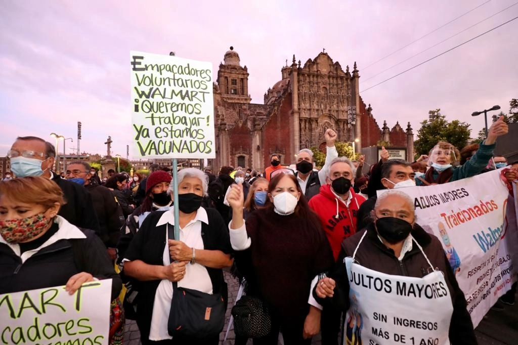 Adultos mayores que se desempeñaban como empacadores voluntarios se manifiestan frente a Palacio Nacional, durante la conferencia presidencial, para denunciar su repudio a Walmart, quien canceló el programa que les permitía laborar en sus sucursales, el 16 de junio de 2021. Foto Roberto García Ortiz