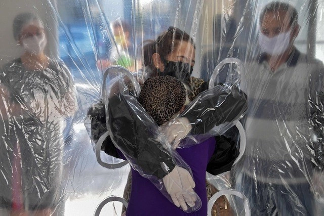 Residentes y visitantes también deben usar guantes protectores negros con mangas largas que llegan hasta los hombros para abrazarse. Foto Afp 
