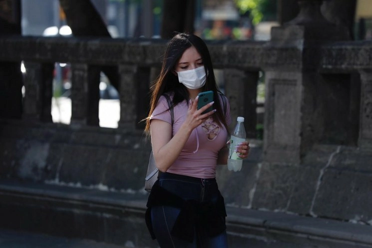 Una mujer utiliza un cubrebocas mientras camina por Paseo de la Reforma, CDMX, para protegerse del coronavirus. Foto Cristina Rodríguez