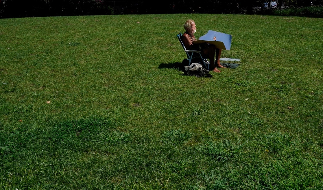 Un hombre toma un baño de sol en Nueva York, en un día de excesivo calor, en el que el termómetro registró 40.5 grados centígrados, el 13 de agosto de 2021. Foto Afp 