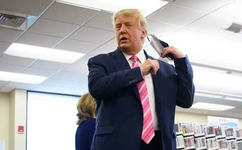  Trump se retira el cubrebocas antes de dirigirse a la prensa luego de votar por anticipado. Foto Afp