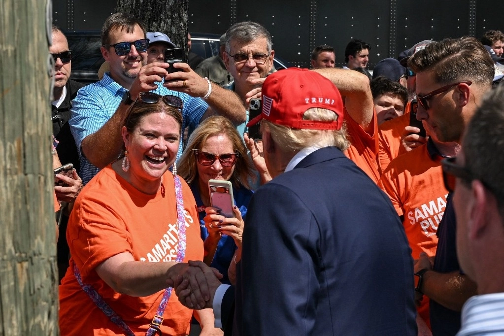 El expresidente estadunidense y candidato presidencial republicano Donald Trump saluda a sus seguidores después de hablar con la prensa tras el paso de la poderosa tormenta Helene en la tienda de muebles Chez What en Valdosta, Georgia, el 30 de septiembre de 2024. Foto Afp