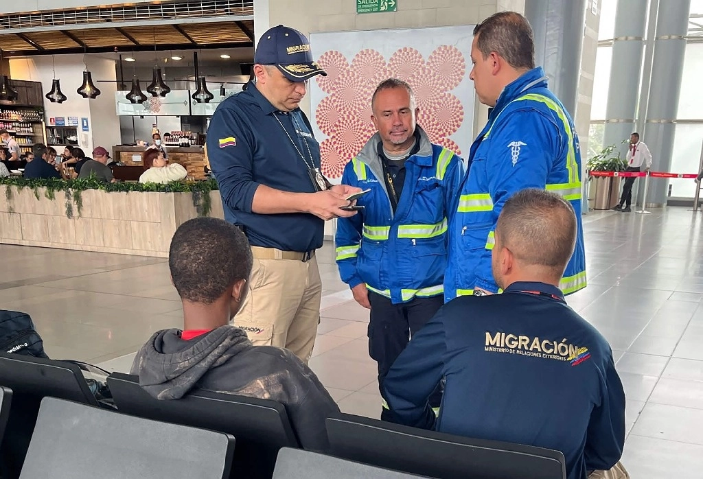 Agentes de la Oficina de Migración de Colombia acompañan a un menor de nacionalidad guineana abandonado en el Aeropuerto Internacional El Dorado de Bogotá el 19 de diciembre de 2023. Foto Afp