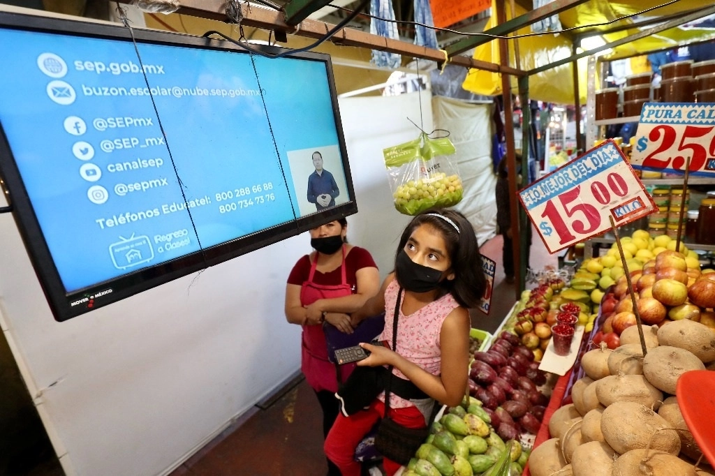 Una niña sintoniza el canal en el que se transmiten las clases del programa Aprende en casa II, desde el local mercantil en el que trabaja su mamá. Foto Luis Castillo / archivo