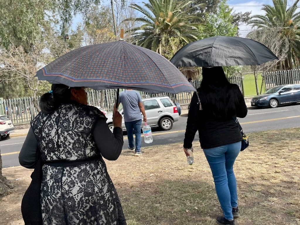 Peatones se protege del sol con sombrillas mientras caminan en una calle de la Ciudad de México. Foto Roberto García Ortiz 