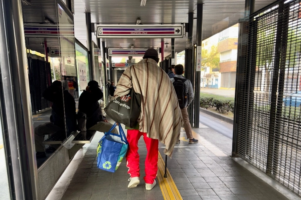 Un usuario del Metrobús se arropa con una cobija para mitigar las bajas temperaturas que se registran en la Ciudad de México, el 19 de diciembre del 2024. Foto Roberto García Ortiz 