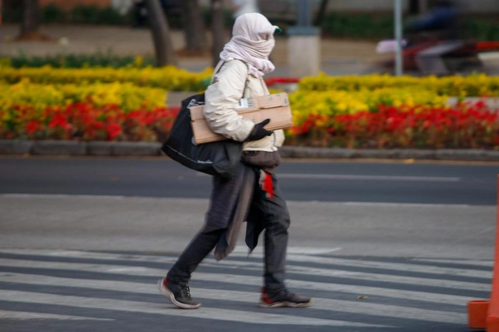 Un hombre, vestido para contrarrestar los efectos del frío intenso que registra la metrópoli, camina por Paseo de la Reforma, el 23 de enero de 2023. Foto Pablo Ramos