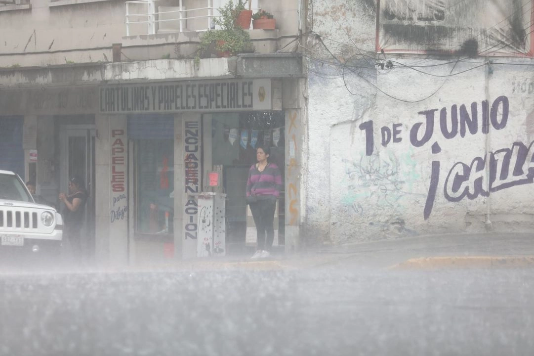 Capitalinos intentan resguardarse de la fuerte lluvia que cae sobre la Ciudad de México, el 12 de junio de 2025. Foto 
