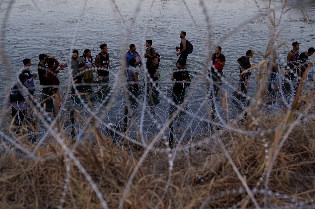 Migrantes esperan trepar una barda fronteriza en el Río Grande, en Eagle Pass, Texas. Foto Ap / Archivo