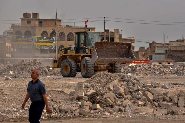 Un trabajador retira escombros con una excavadora en la antigua ciudad de Mosul, al norte de Irak. Foto Afp 