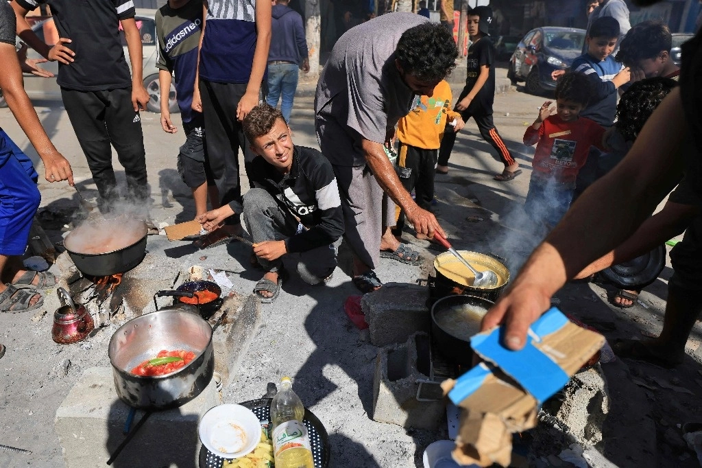 Palestinos desplazados preparan comida frente a una escuela de la Agencia de la ONU para los refugiados palestinos, en un campamento en la franja de Gaza, el 7 de noviembre de 2023. Foto Afp 