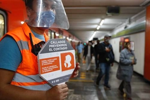 En la estación Hidalgo del Metro, un empleado muestra una paleta con la nueva disposición de no hablar, como parte del regreso a la nueva normalidad. Foto Roberto García Ortiz